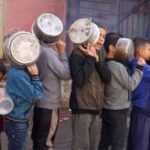 bambini palestinesi in coda per ricevere cibo